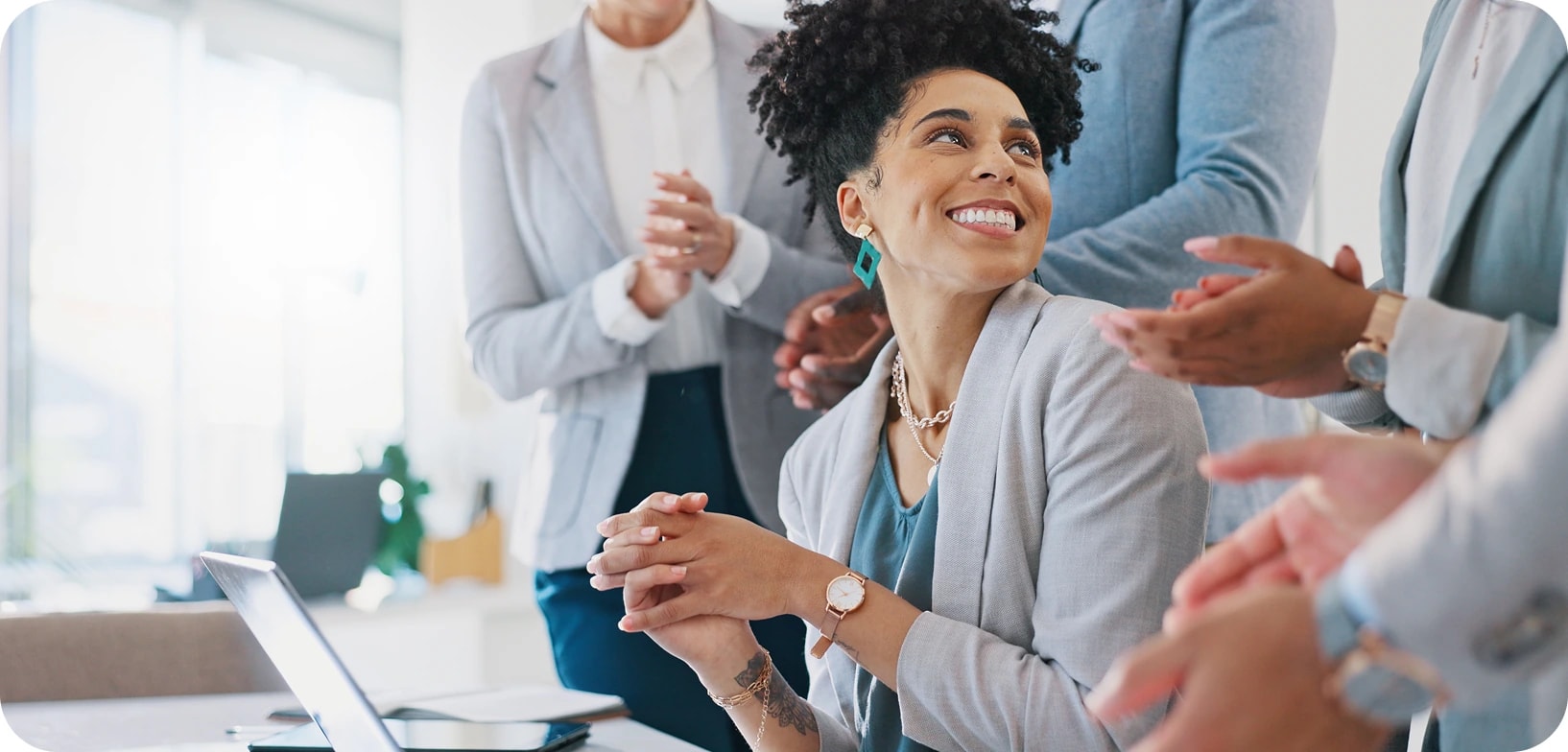 AM InfoWeb colleagues applauding a teammate during a meeting, reflecting the everyday recognition and shared moments of life at AMI.